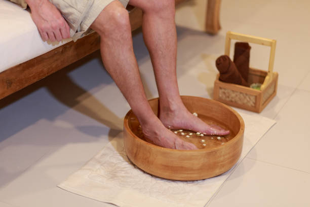 young man soaking feet in a bowl waiting spa staff to clean.