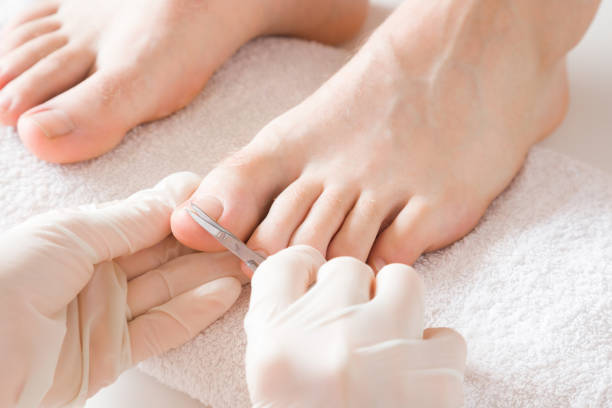 Pedicurist's hands in protective rubber gloves cutting toenails with scissors. Cares about man's feet. Specialist with client in beauty salon. Professional beauty service. Pedicure, manicure concept.